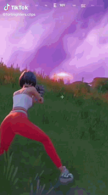 a woman is holding a gun in a video game while standing in the grass .