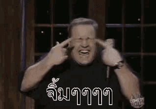 a man is laughing and covering his eyes with his hands .