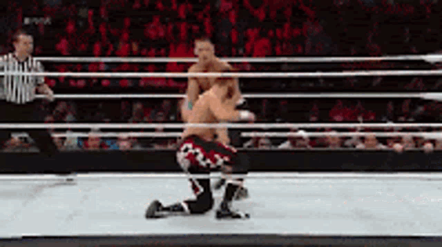 two wrestlers are wrestling in a ring with a referee in the background