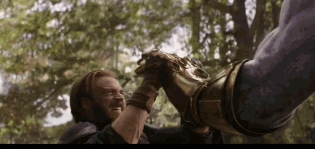 a man is holding a glove in his hand while fighting thanos .