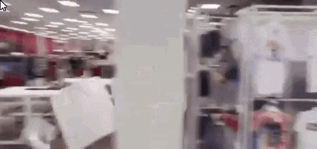 a blurry picture of a store filled with lots of clothes and a arrow pointing to the right .