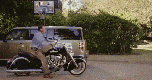 a man is standing on a motorcycle in front of a van .