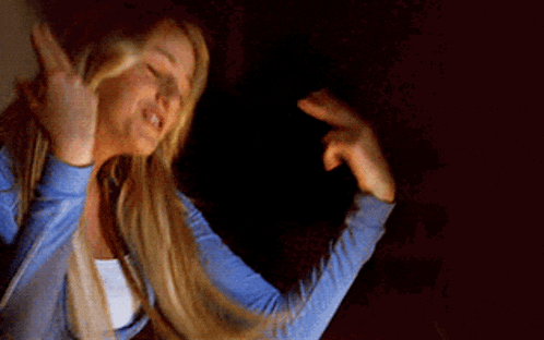 a woman with long blonde hair is smiling and making a peace sign