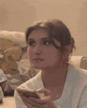 a woman is sitting on a couch looking at her cell phone