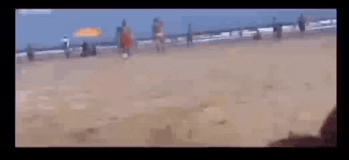 a man is kneeling on the beach holding a banana
