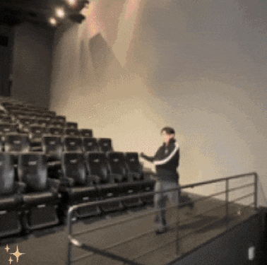 a man is standing in an auditorium with rows of seats and a railing
