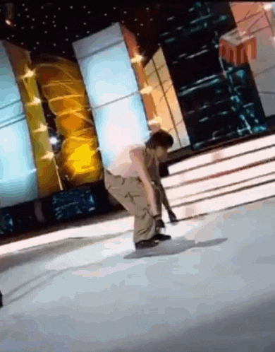 a man is doing a trick on a stage while a woman watches .