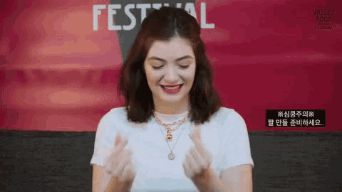 a woman is making a heart shape with her hands and smiling .