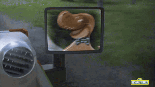 a sesame street character wearing a hat is driving a vehicle