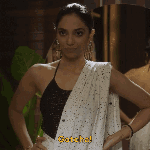 a woman wearing a black top and a white saree says gotcha in yellow letters