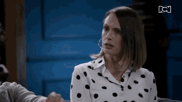 a woman in a polka dot shirt is sitting on a couch