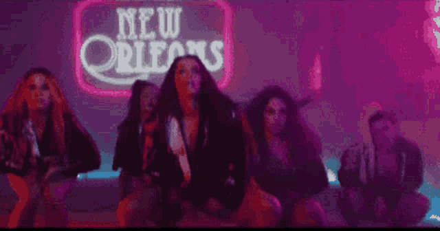 a group of women are standing in front of a neon sign that says new orleans .