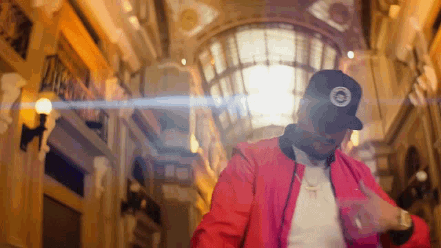 a man wearing a red jacket and a black hat is dancing