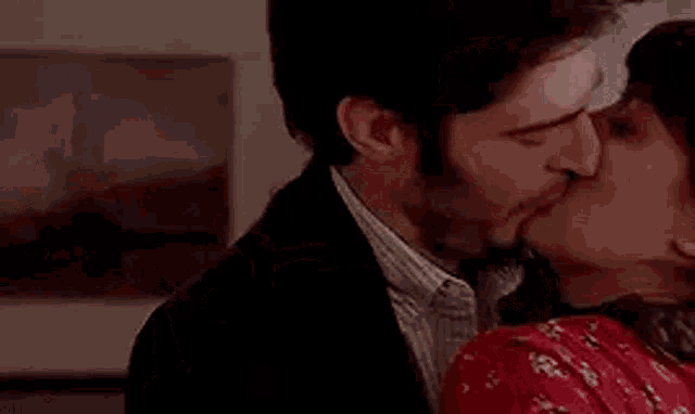 a man and a woman are kissing in a room while sitting in a chair .