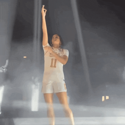 a woman in a number 11 jersey holds up her hand