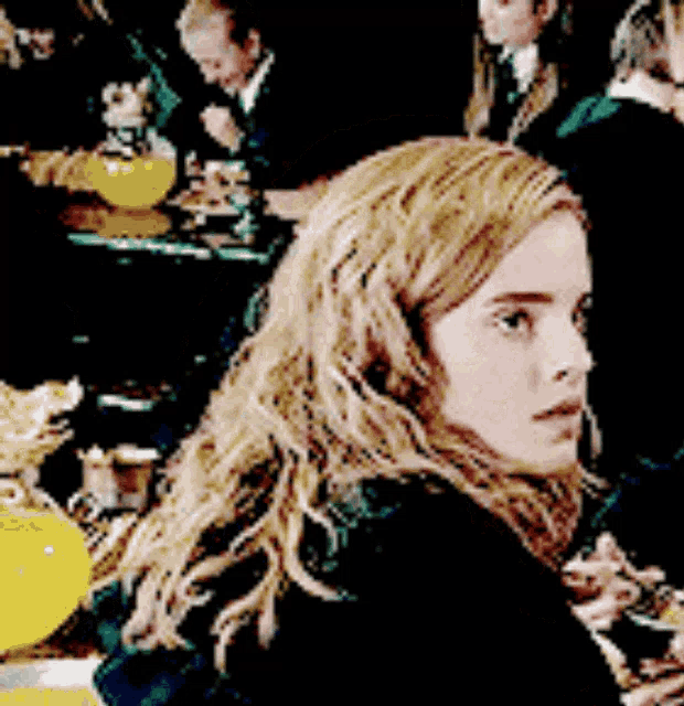 a woman with long blonde hair is sitting at a table with other people .
