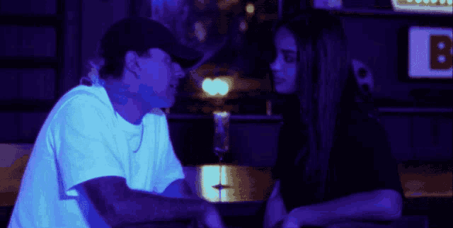 a man and a woman are sitting at a table in front of a sign that says b.