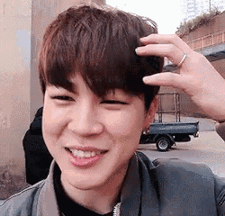 a young man with a ring on his finger is smiling and touching his head .