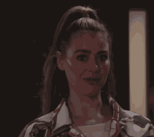 a woman with her hair in a ponytail is wearing earrings