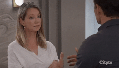 a man and a woman are talking to each other and the woman is wearing a white shirt .
