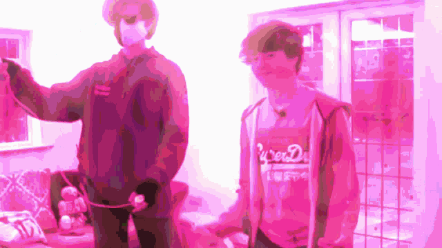 a man wearing a shirt that says ' superdry ' on it stands next to another man