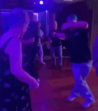 a group of people are dancing on a dance floor in a room .