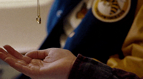 a close up of a person 's hand holding a pendant
