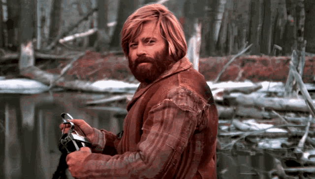 a man with red hair and a beard is holding a camera
