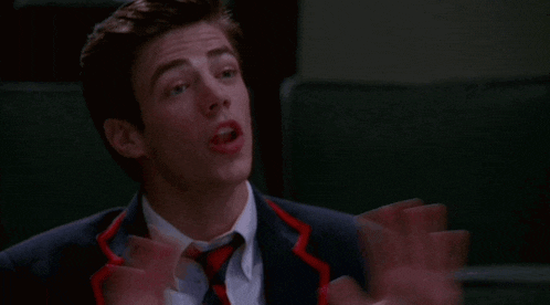 a man in a suit and tie is making a face with his hands outstretched