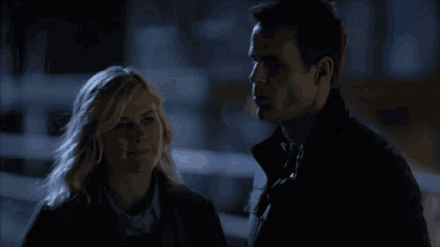 a man and a woman standing next to each other in the dark