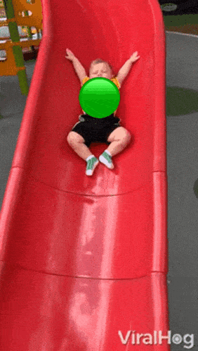 a child is sliding down a red slide wearing a yellow shirt that says snoopy on it