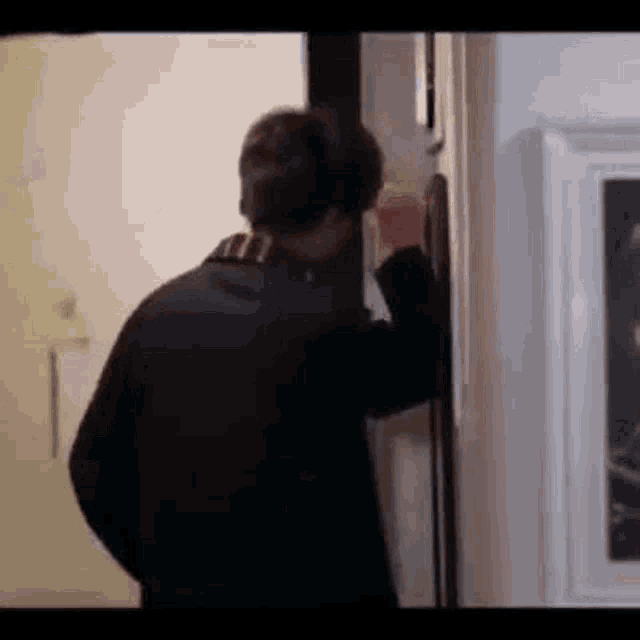 a man is standing in a doorway talking on a phone .