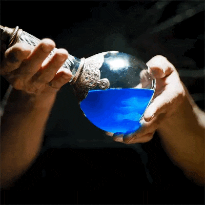 a person is pouring blue liquid into a glass container