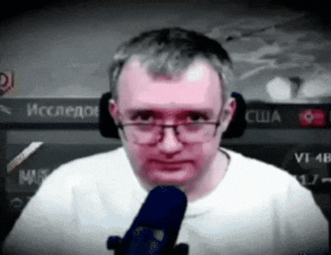 a man with glasses is sitting in front of a microphone .