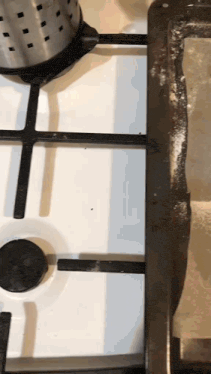 a white stove top with a black burner and a black handle