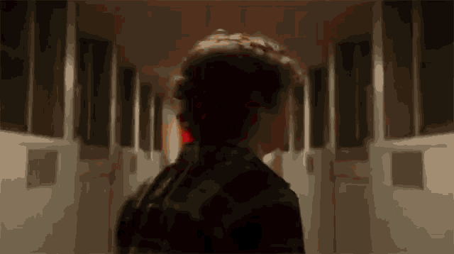 a man is walking down a hallway in a dark room .