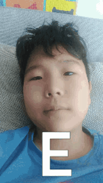 a young boy laying on a couch with a white letter e on his face
