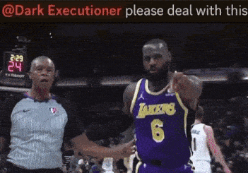 a basketball player wearing a lakers jersey is pointing at the referee