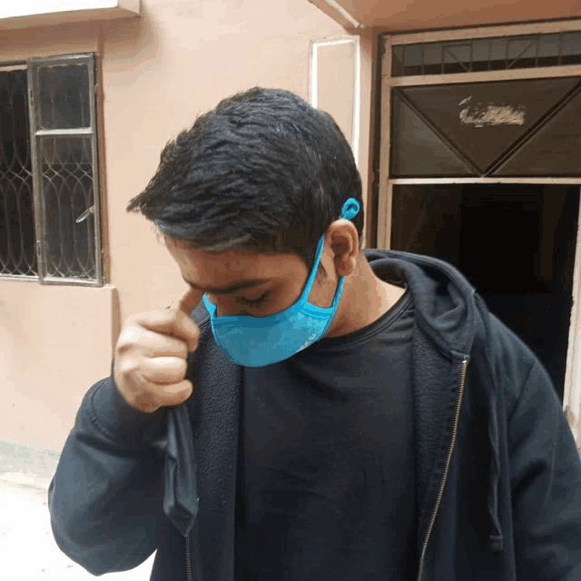 a man wearing a blue face mask is covering his face