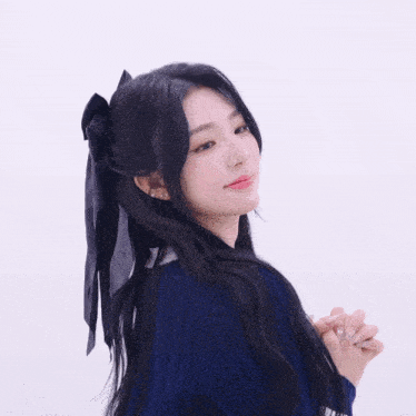 a woman in a blue sweater has a black ribbon in her hair