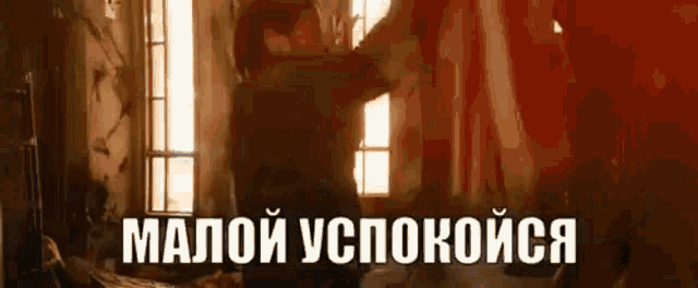 a man is standing in front of a window in a room with russian writing on the bottom .