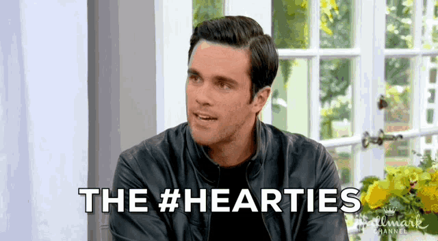 a man in a leather jacket is sitting in front of a window and says the #hearties .