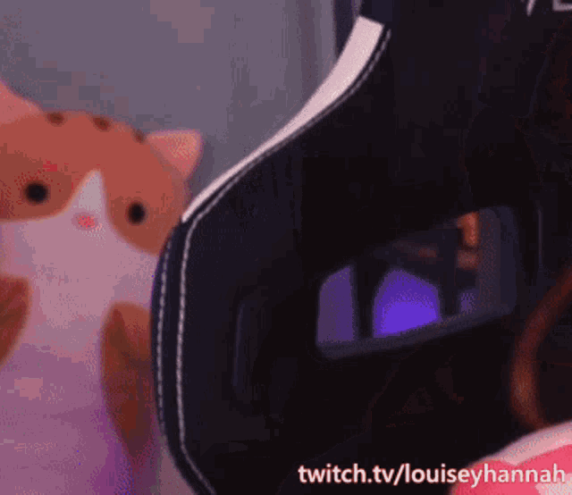 a person is sitting in a chair with a stuffed cat in the background and a twitch.tv/louiseyhannah watermark