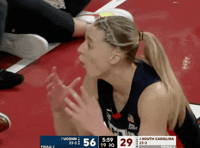 a female basketball player sitting on the floor during a game between ucconn and south carolina