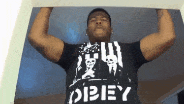 a man wearing a black shirt with the word obey on it