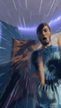 a man in a blue tie dye shirt is standing in a room with a blurred background .