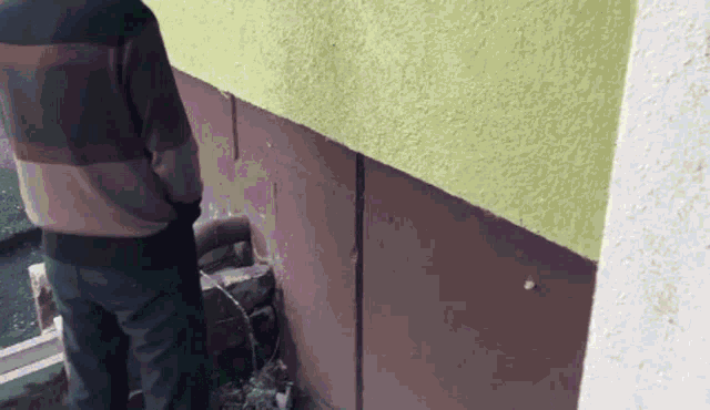 a man in a striped sweater is urinating on the side of a building