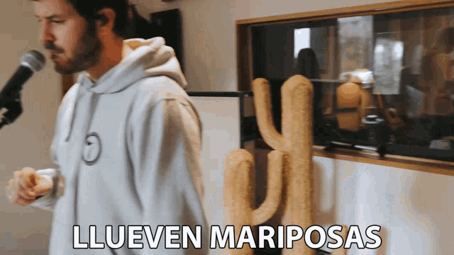 a man singing into a microphone with the words llueven mariposas written above him