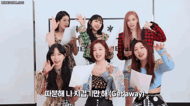 a group of girls are posing for a picture and one of them is holding a piece of paper that says get away