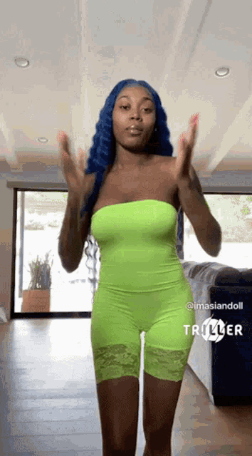 a woman in a neon green jumpsuit stands in front of a couch